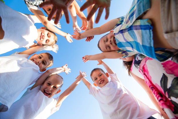 Groupe d'enfants heureux de garçons et de filles dans la vue du parc depuis le sol