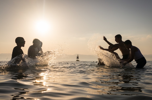 Groupe d&#39;enfants heureux jouant et éclaboussant dans la plage de la mer.