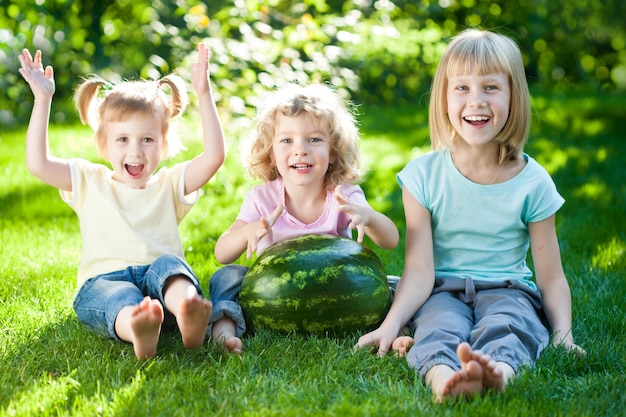 Groupe d'enfants heureux jouant à l'extérieur dans le parc du printemps