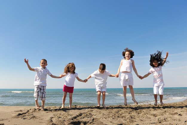 groupe d'enfants heureux sur la plage qui s'amusent et jouent à des jeux