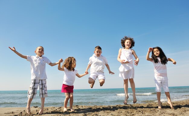 groupe d'enfants heureux sur la plage qui s'amusent et jouent à des jeux