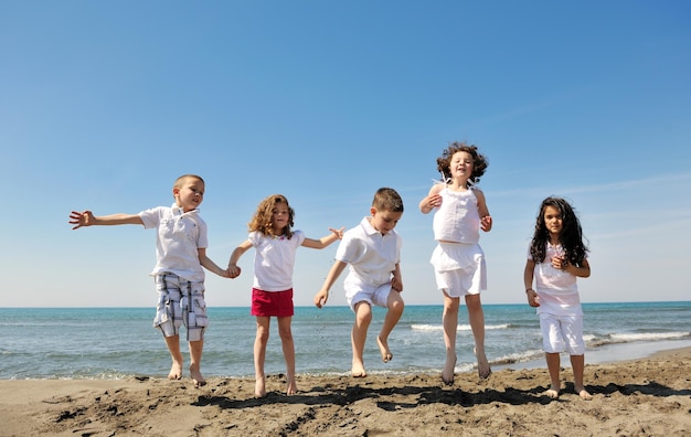 groupe d'enfants heureux sur la plage qui s'amusent et jouent à des jeux