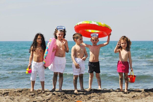 groupe d'enfants heureux s'amuser sur la plage tout en jouant avec des jouets courir sauter