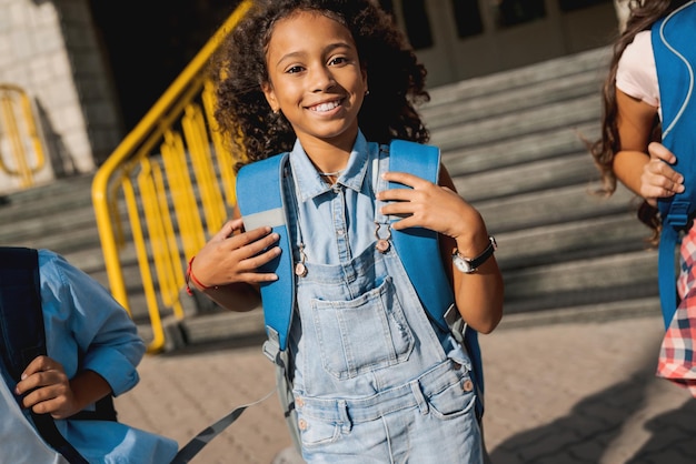 Groupe d'enfants heureux avec des sacs à dos marchant dans la cour de l'école