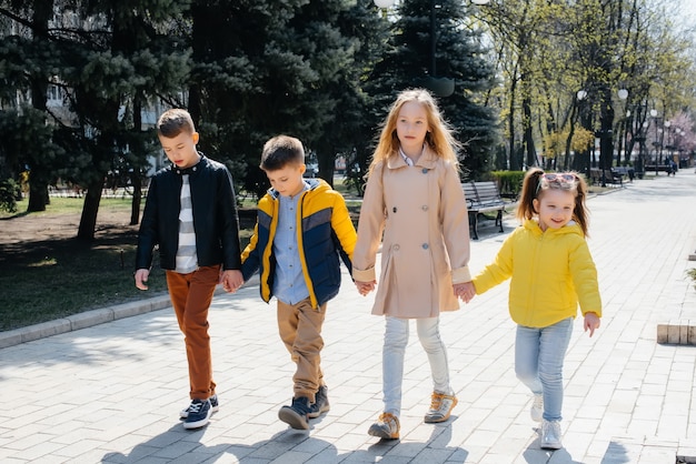 Un groupe d'enfants joue ensemble et marche dans le parc en se tenant la main. Amis, enfants.