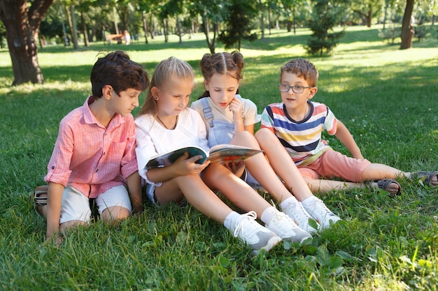 Groupe D'enfants Lisant Un Livre Ensemble à L'extérieur Dans Le Parc