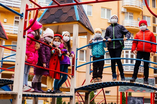 Un groupe d'enfants marche sur l'aire de jeux avec des masques de protection
