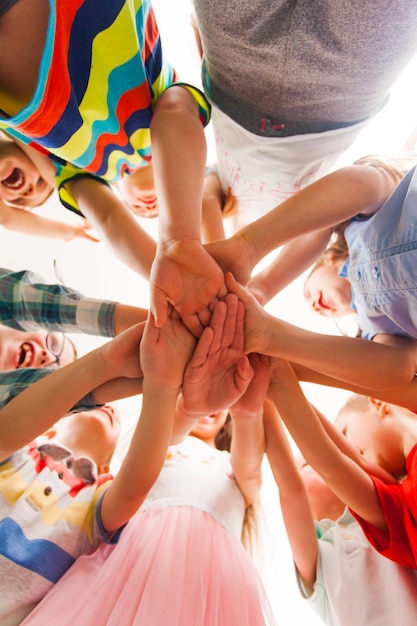 Groupe d'enfants mettant leurs mains ensemble. Vue du bas