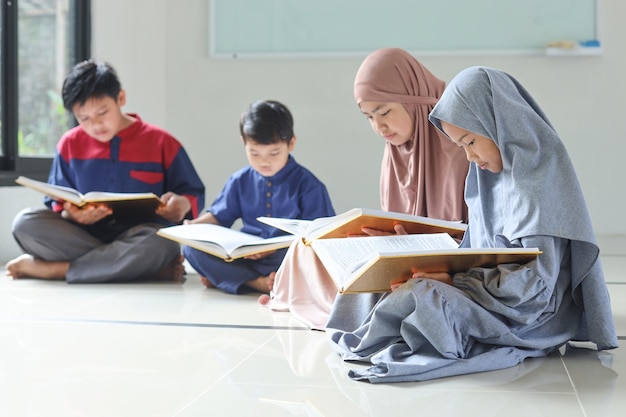 Groupe d'enfants musulmans lisant des livres saints Coran ensemble à la mosquée