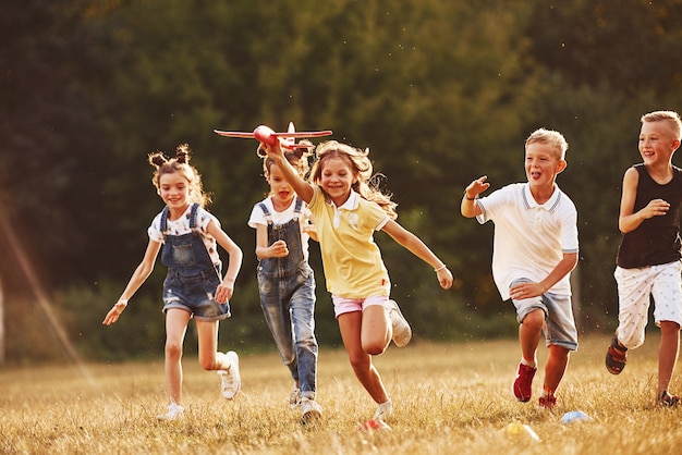 Groupe d'enfants s'amusant à l'extérieur avec un avion jouet rouge dans les mains.