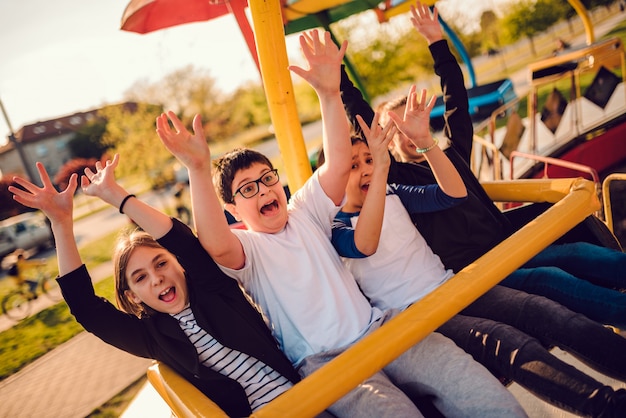 Groupe d'enfants sur un tour de spinning dans un parc d'attractions