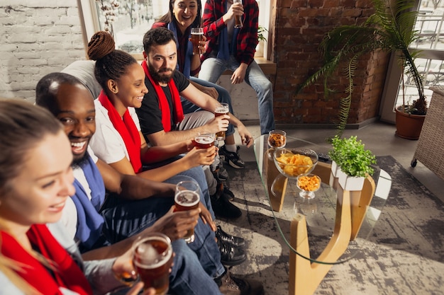 Groupe enthousiaste de personnes regardant le football, match de sport à la maison