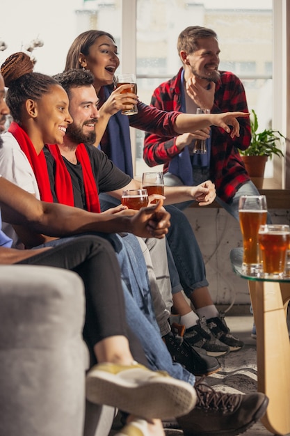 Groupe enthousiaste de personnes regardant le football, match de sport à la maison