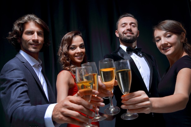 Groupe d'équipe d'affaires heureuse portant un toast au champagne sur fond noir