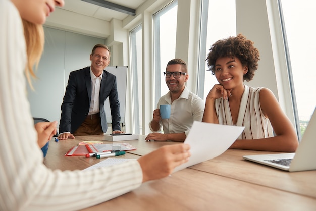 Groupe d'équipe multiculturelle de jeunes gens d'affaires regardant des documents et discutant de quelque chose