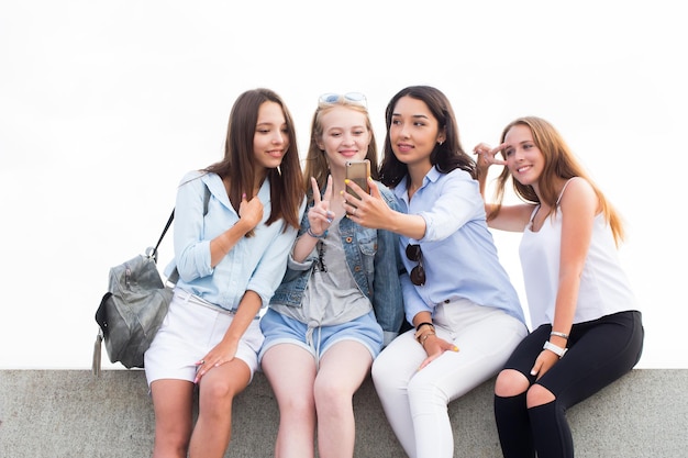 Un groupe d'étudiantes dans le parc. Une belle femme brune montre quelque chose à ses amis sur son smartphone. Concepts d'amitié et de technologie moderne