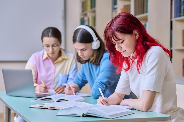 Groupe d'étudiants adolescents étudient à leur bureau en classe de bibliothèque