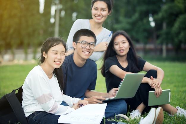 Groupe d&#39;étudiants asiatiques partageant les idées pour travailler sur la pelouse du campus