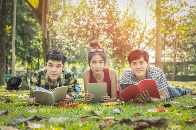 Groupe d&#39;étudiants couché sur l&#39;herbe lire un livre dans le parc