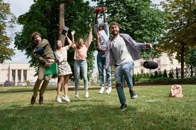 Groupe d'étudiants joyeux debout sur l'herbe dans le parc