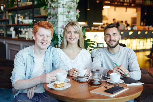 Groupe d'étudiants joyeux de l'université se détendre dans un café après les cours, prendre le thé et profiter d'être ensemble