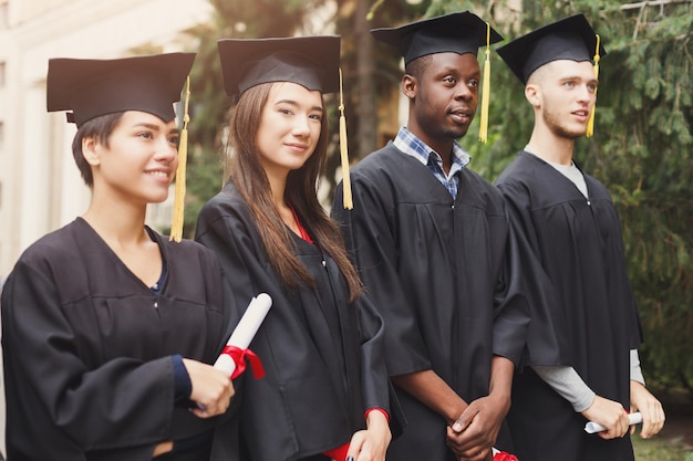 Un groupe d'étudiants multiethniques célébrant leur diplôme. Concept d'éducation, de qualification et de robe.