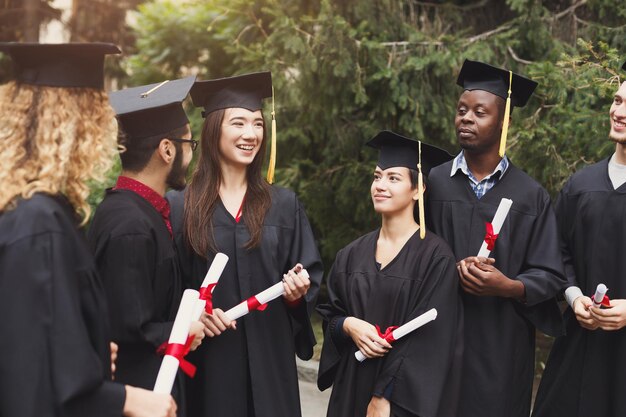 Un groupe d'étudiants multiethniques célébrant leur diplôme. Concept d'éducation, de qualification et de robe.