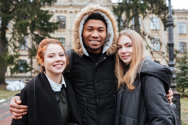 Groupe d'étudiants multiethniques heureux se tenant ensemble à l'extérieur sur le campus universitaire