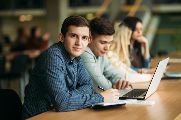 Groupe d'étudiants qui étudient à la bibliothèque de l'école une fille et un garçon utilisent un ordinateur portable et