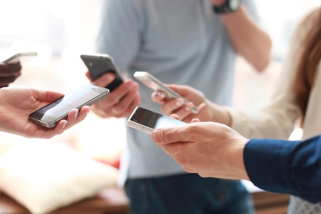 Groupe d'étudiants regardant des smartphones. Dépendance des jeunes aux nouvelles tendances technologiques.