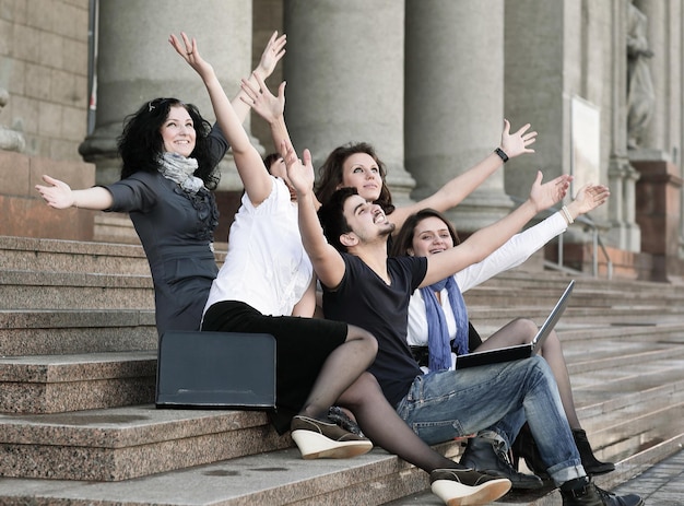 Groupe d'étudiants universitaires heureux devant le bâtiment de l'université