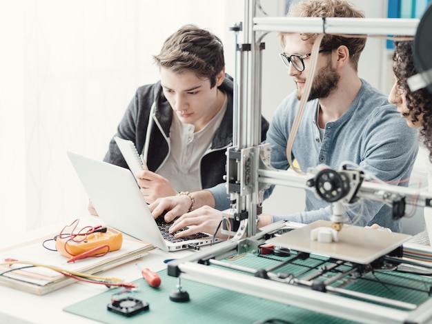 Groupe d'étudiants utilisant une imprimante 3D et un ordinateur portable