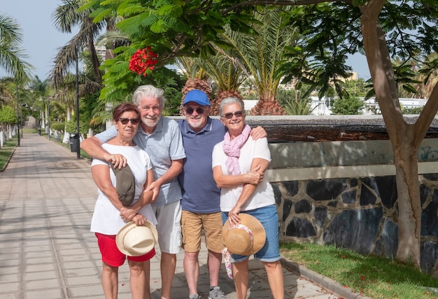 Groupe familial de quatre personnes âgées profitant d'une journée ensoleillée en vacances en plein air s'embrassant dans le parc public