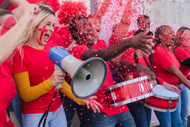 Photo groupe de fans d'une équipe applaudissant avec une grande joie et utilisant des confettis célébrant les succès de leur équipe