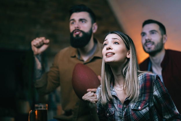 Groupe de fans de sport regardant un match de rugby à la télévision à la maison L'accent est mis sur la femme au premier plan