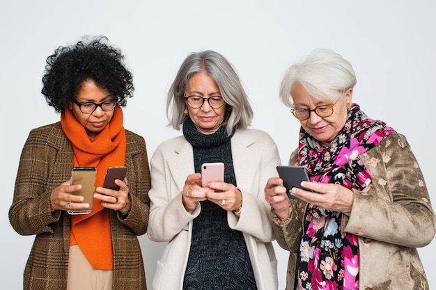 Un groupe de femmes d'âge moyen regardant des smartphones sur un fond blanc