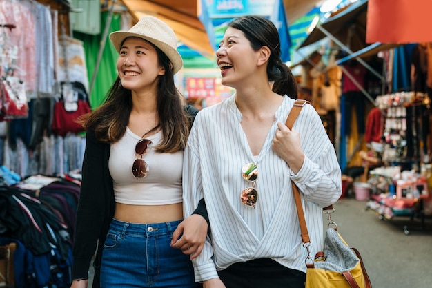 groupe de femmes coréennes asiatiques faisant du shopping et marchant à taipei taiwan. deux filles voyageuses s'amusant en ville tout en visitant le marché traditionnel local. amis touristes partageant des moments heureux ensemble