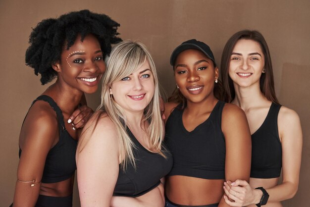 Groupe de femmes multiethniques debout dans le studio sur un fond brun