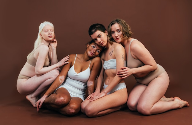Groupe de femmes multiethniques avec différents types de peau posant ensemble en studio. Concept sur la positivité corporelle et l'acceptation de soi