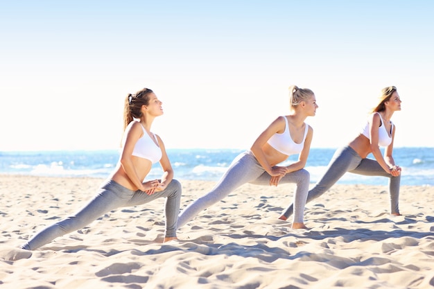 groupe de femmes pratiquant le yoga sur la plage