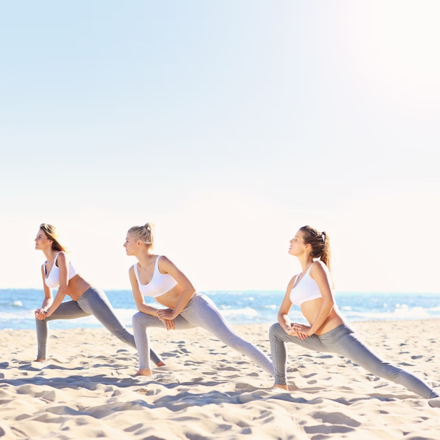 groupe de femmes pratiquant le yoga sur la plage