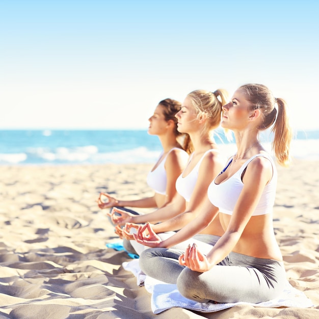 groupe de femmes pratiquant le yoga sur la plage