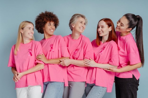 Photo groupe de femmes souriantes avec un ruban rose embrassant isolées sur fond de sensibilisation au cancer du sein