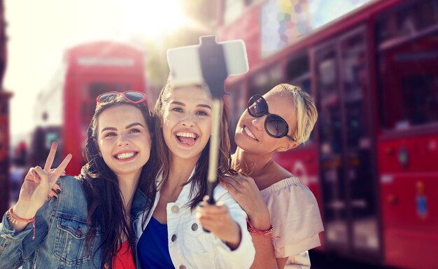 Un groupe de femmes souriantes se faisant des selfies à Londres.