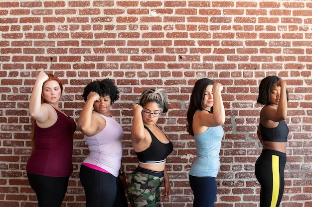 Groupe de femmes sportives debout près d'un mur de briques