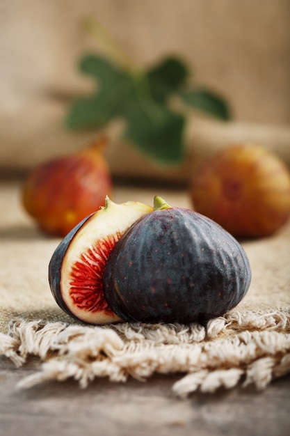 Groupe de figues violettes et vertes sur une table en bois de ferme avec toile de jute