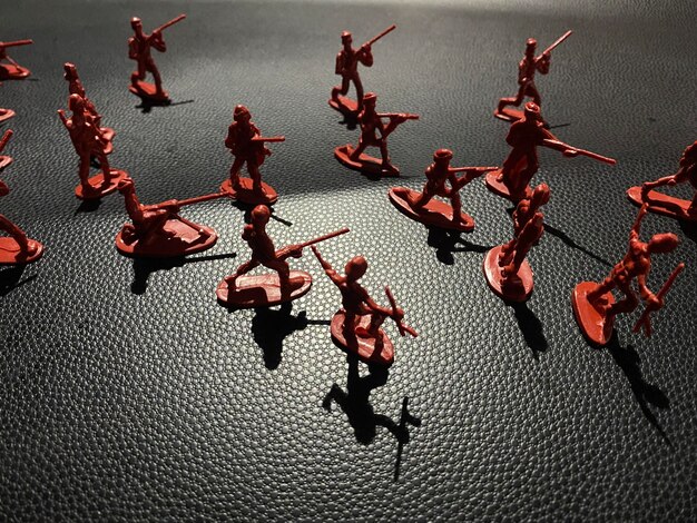 Un groupe de figurines en plastique rouge se trouve sur une surface noire.