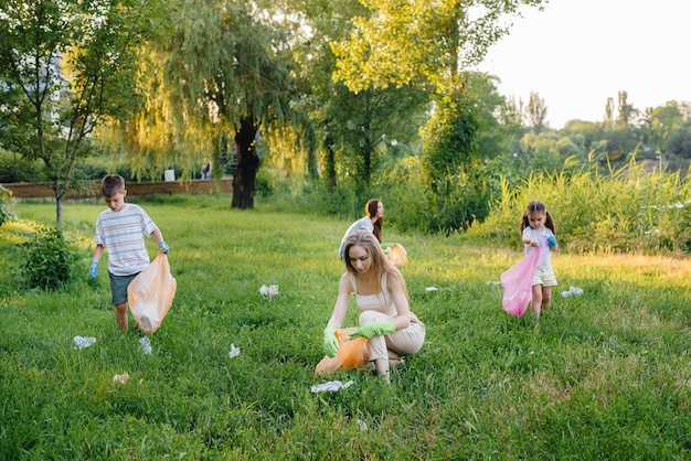 Un groupe de filles avec des enfants au coucher du soleil s'occupe de la collecte des ordures dans le parc. Respect de l'environnement, recyclage.