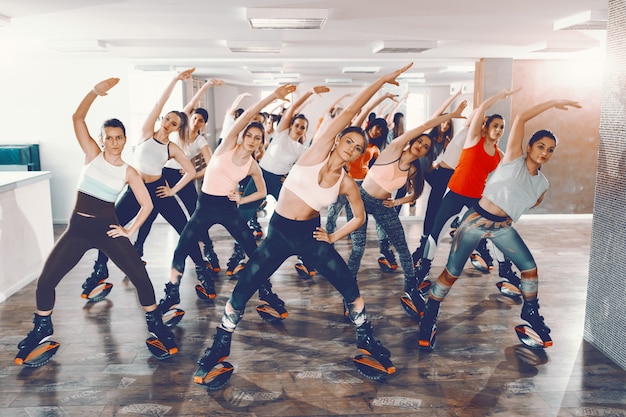 Groupe de filles avec des habitudes saines faisant des exercices dans des chaussures de sauts kangoo. Votre corps peut le faire, c'est votre esprit qu'il vous faut convaincre.