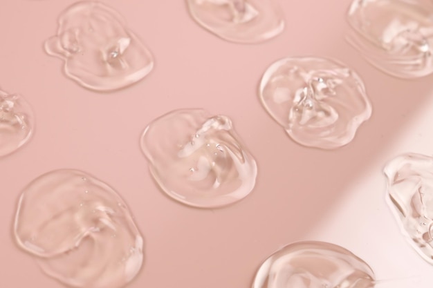 Groupe de frottis de gel transparent sur fond rose pastel Produit de soin d'hygiène texture crémeuse